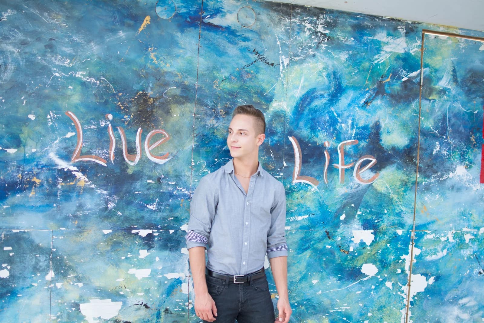 Jordan in front of a blue mural reading Live Life.