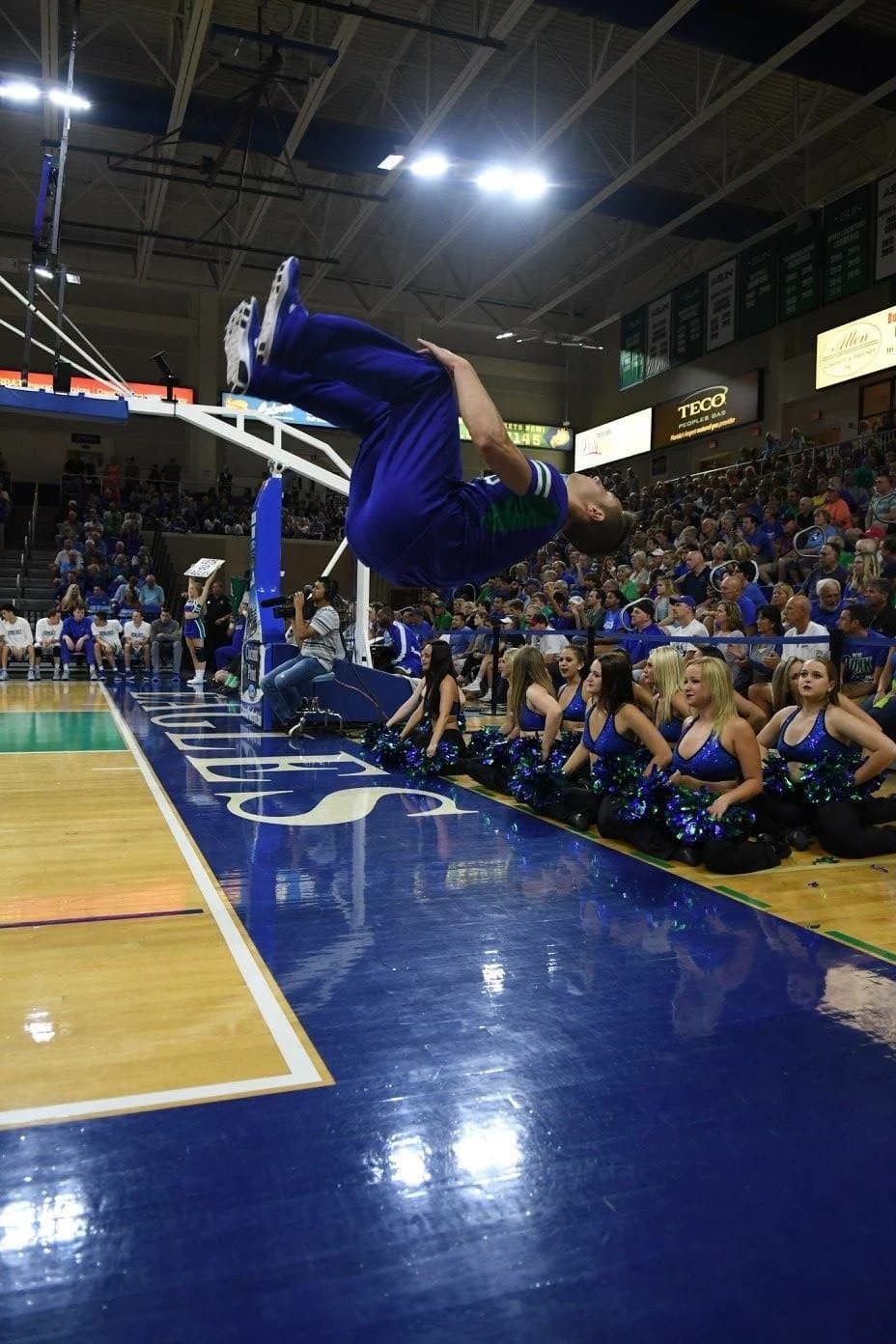 Jordan airborne above the basketball court during a cheer performance.