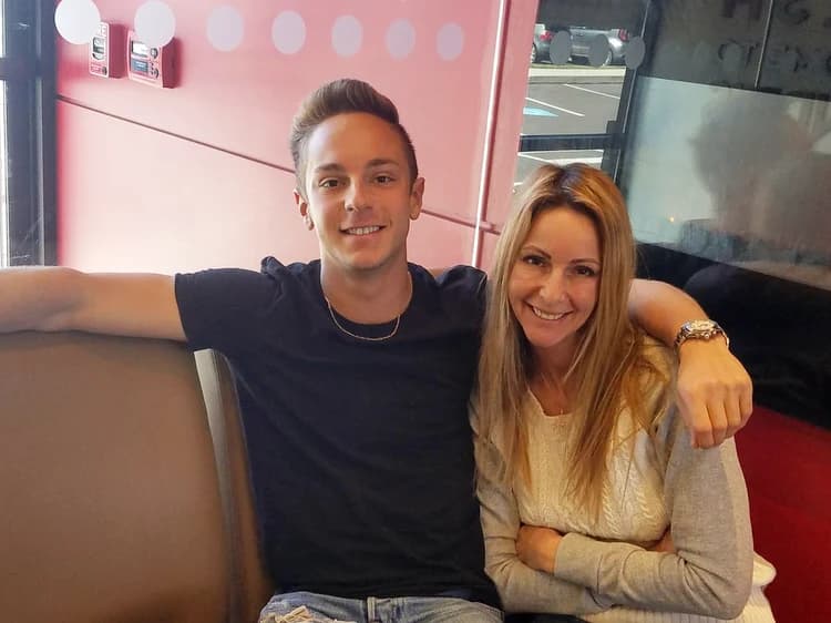 Jordan and his mom smiling together in a restaurant booth.
