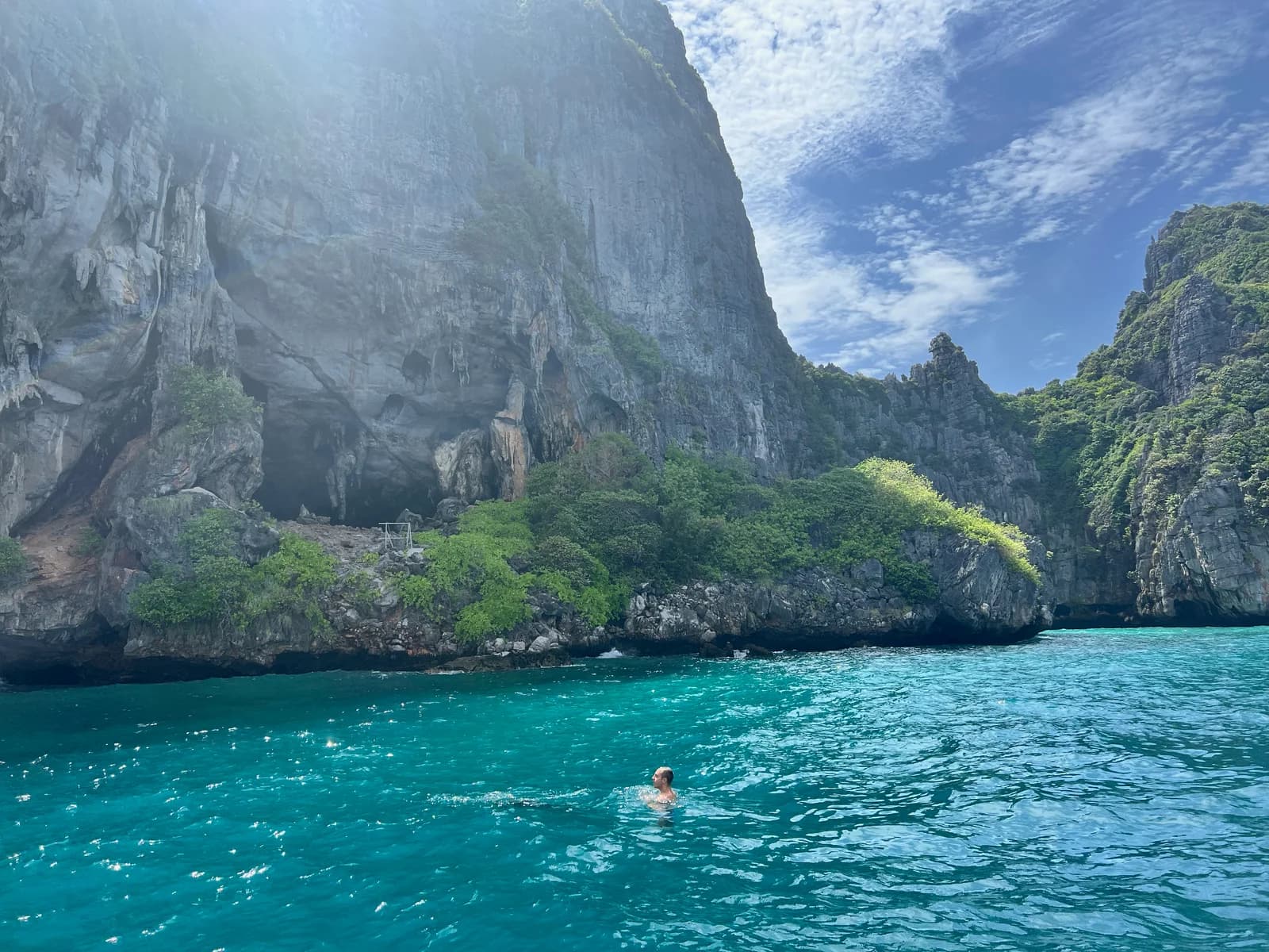 Sunlight and blue water below the green limestone cliffs.