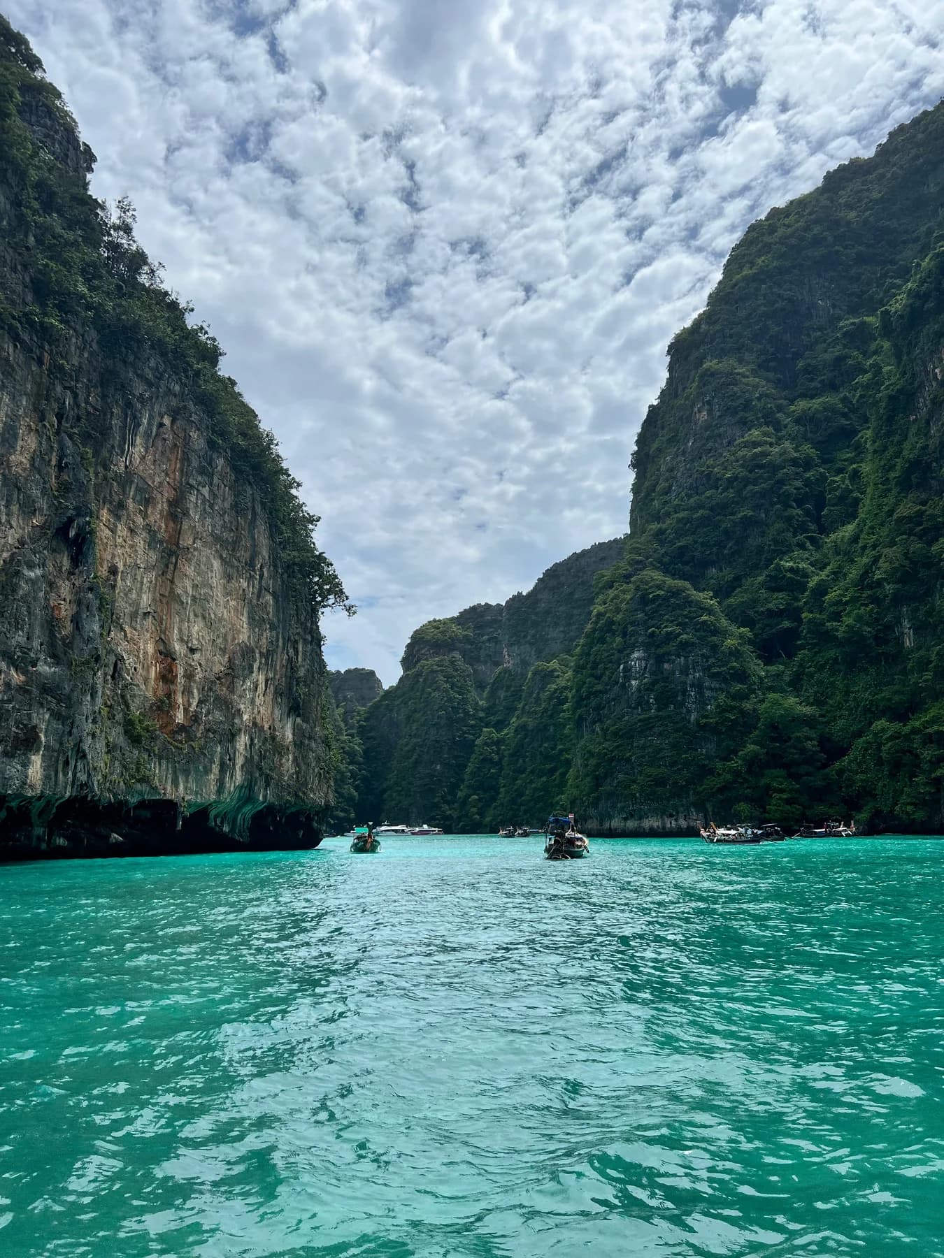 A narrow stretch of turquoise sea between towering limestone cliffs.