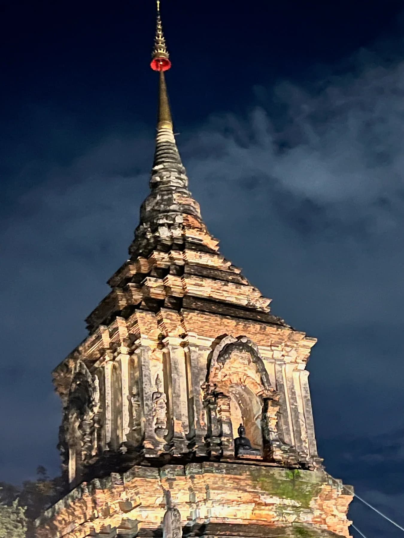 An illuminated temple spire against the evening sky in Chiang Mai.