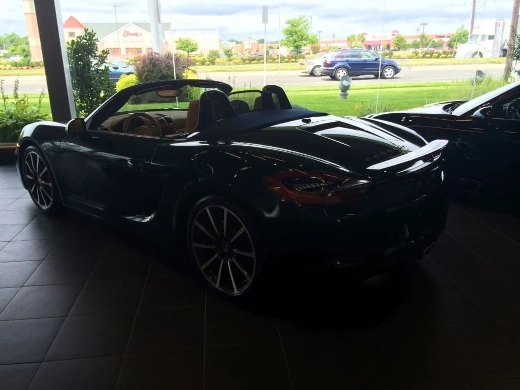 A dark blue Porsche Boxster with its roof down in a showroom.