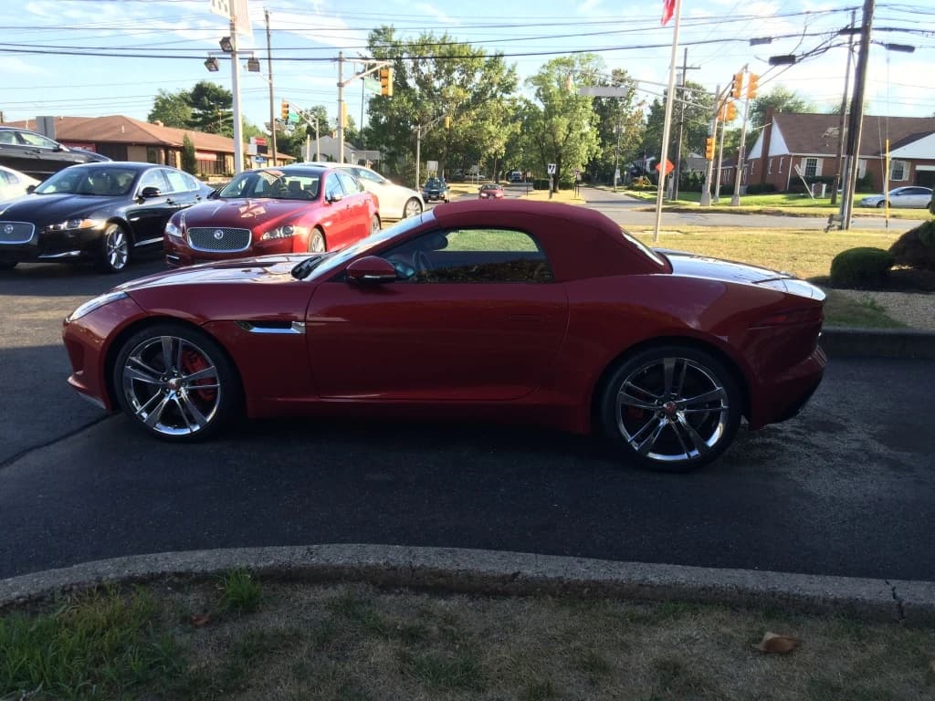 A red Jaguar convertible, photographed from the side.