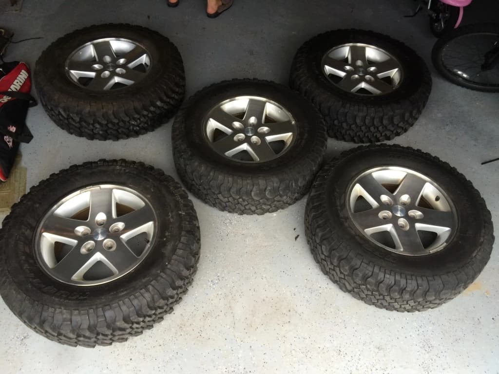 Five Jeep wheels and tires laid out together.